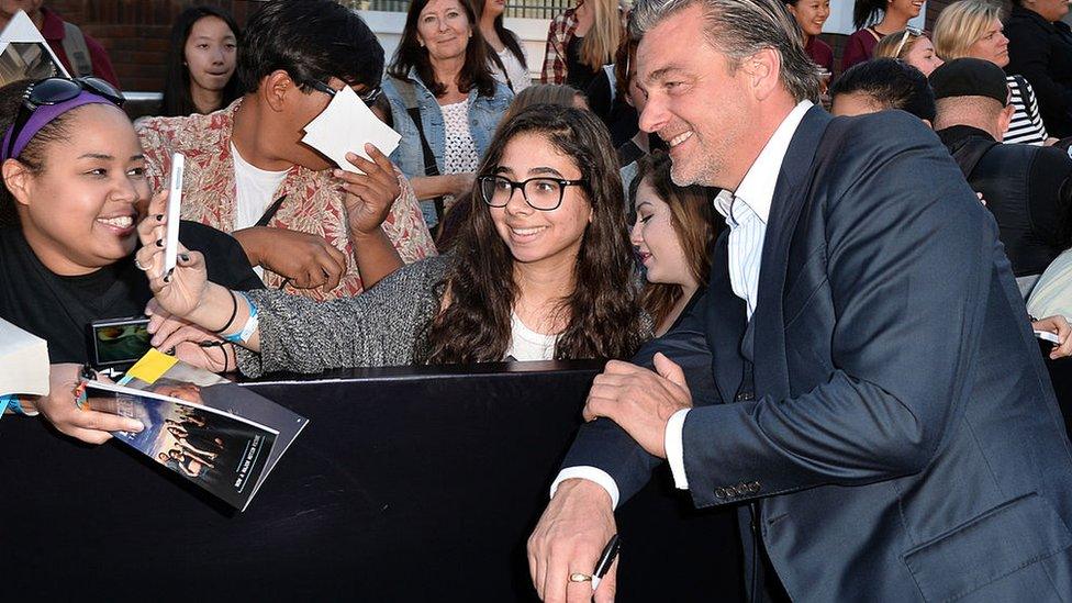 Ray Stevenson poses for a photo with a fan on the red carpet in Los Angeles