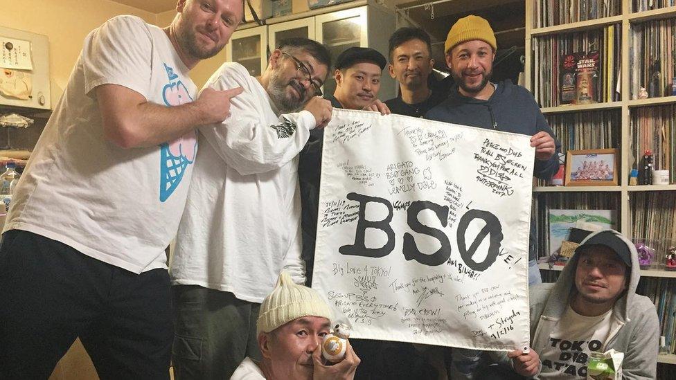 Image of Bristol artists and Mr Iijima holding flag reading BS0.