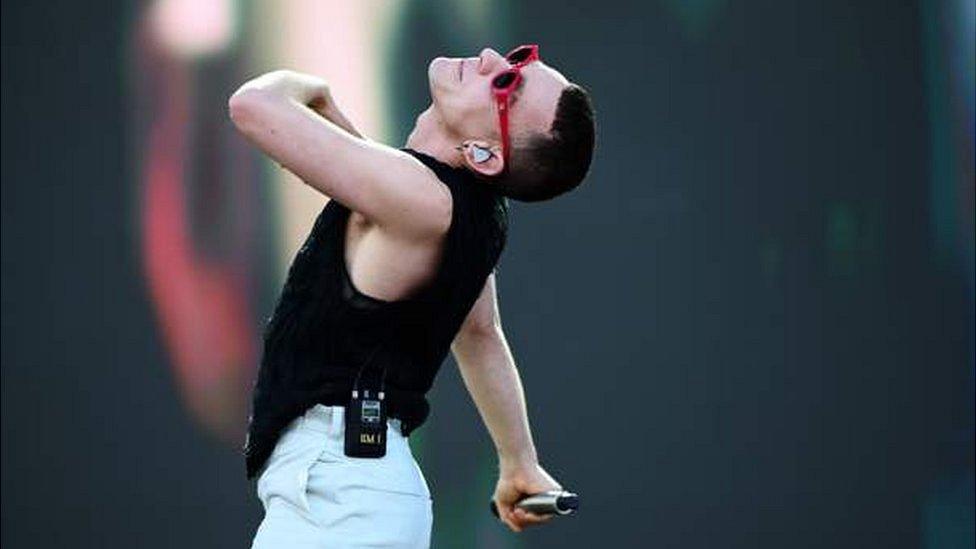 Olly Alexander performs in red sunglasses.
