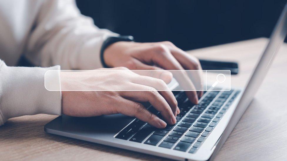 A person types on a laptop computer