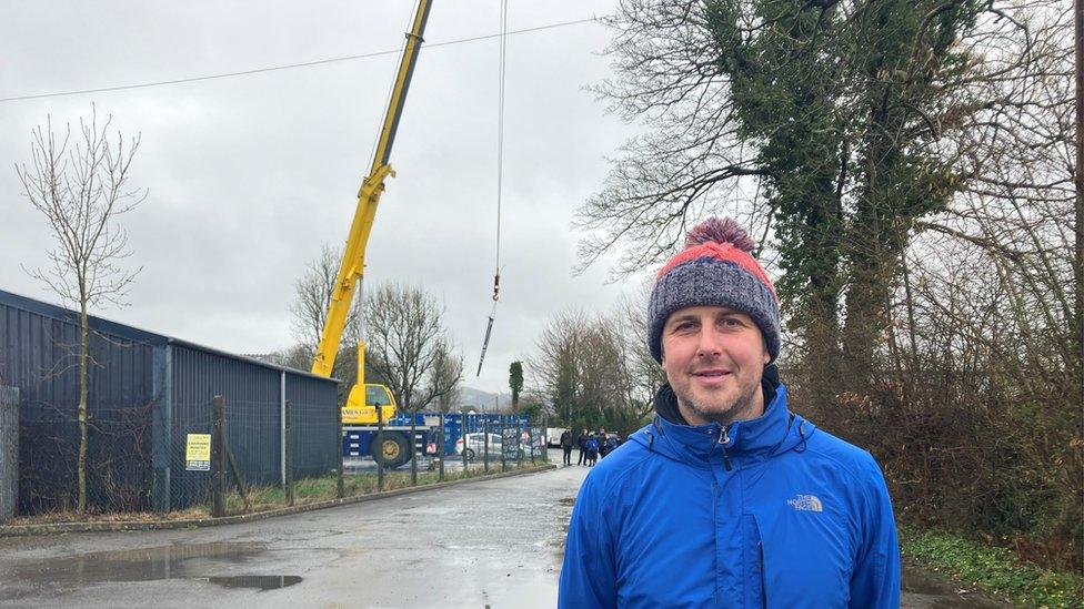 Farmer Dyfan Walters standing in front of a large yellow crane