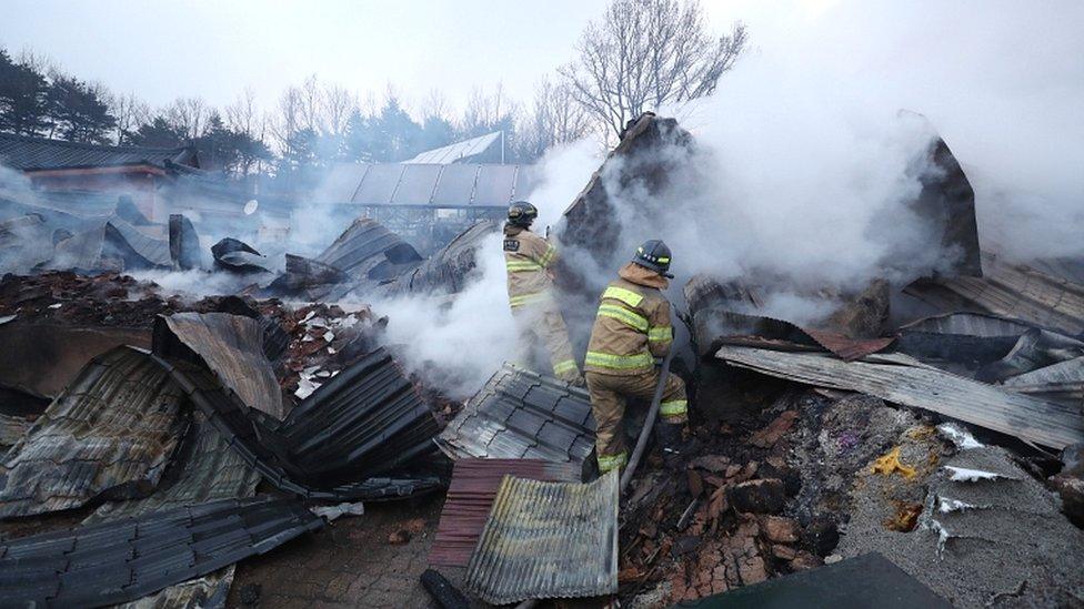 Firefighters try to extinguish a still burning house gutted by a massive forest fire in Sokcho, South Korea, on 5 April 2019