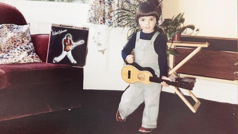 A young Samuel Smith with a small guitar in his hand