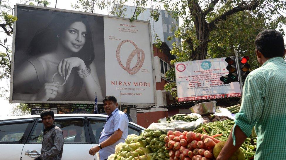 Indians walk past a billboard with a picture of Bollywood actress Priyanka Chopra promoting the luxury jewellery store Nirav Modi in Mumbai on February 15, 2018