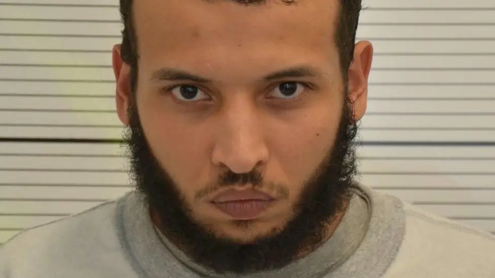 A mugshot of Khairi Saadallah, who has dark, short hair and a dark beard.