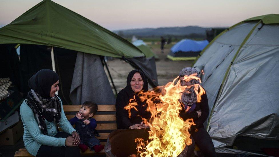 Syrian refugee women gather around bonfire at makeshift camp on Greek-Macedonian border. March 31, 2016