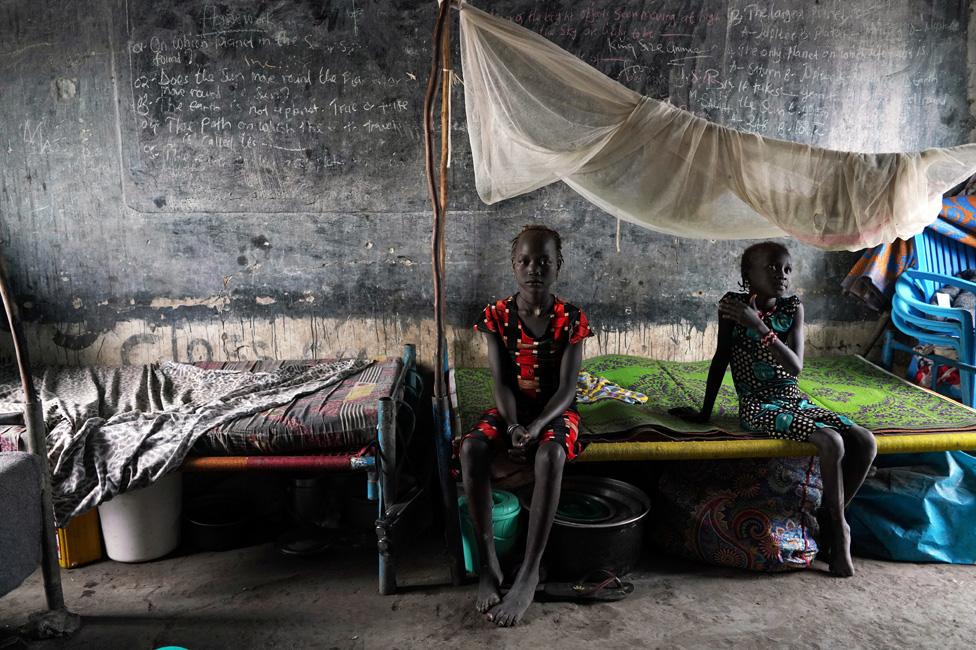 Displaced girls sit on a bed in a classroom, in a school now occupied by IDPs (Internally Displaced People) after heavy rains and floods