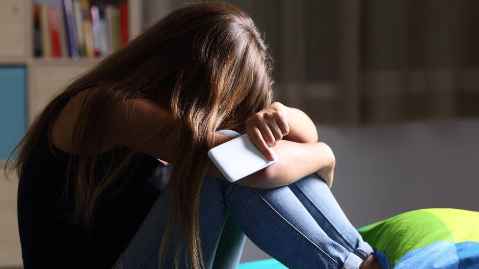 Picture of upset teen holding phone