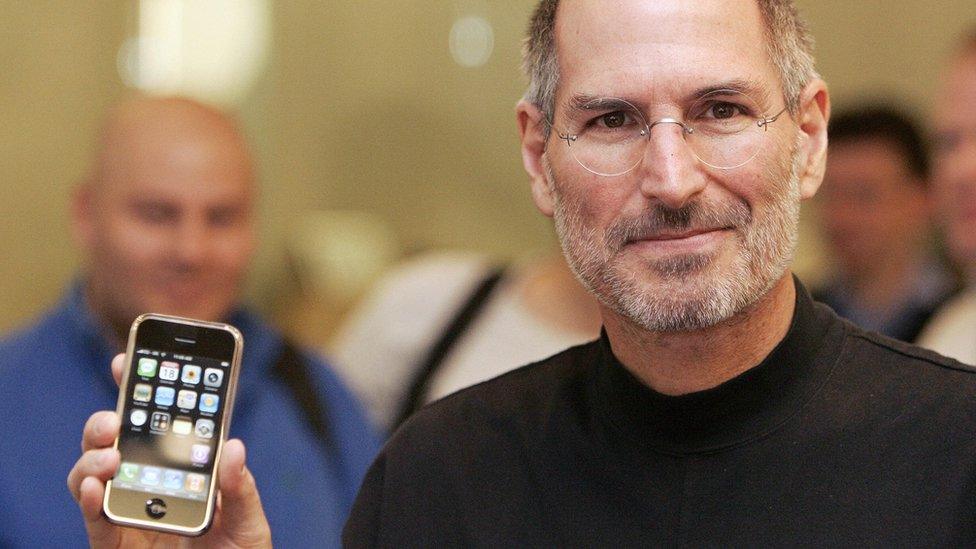 Late Apple boss Steve Jobs holds up the first iPhone