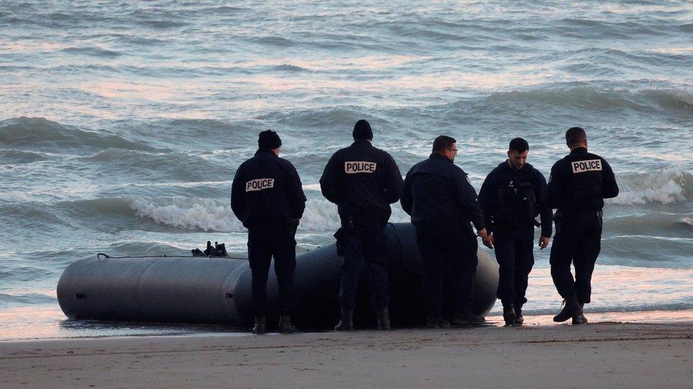 Police in Sangatte, France stand by a dinghy that had tried to cross the English Channel.