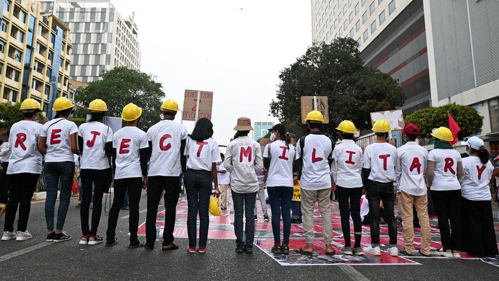 Demonstrators stand in line as they form a message with their t-shirts