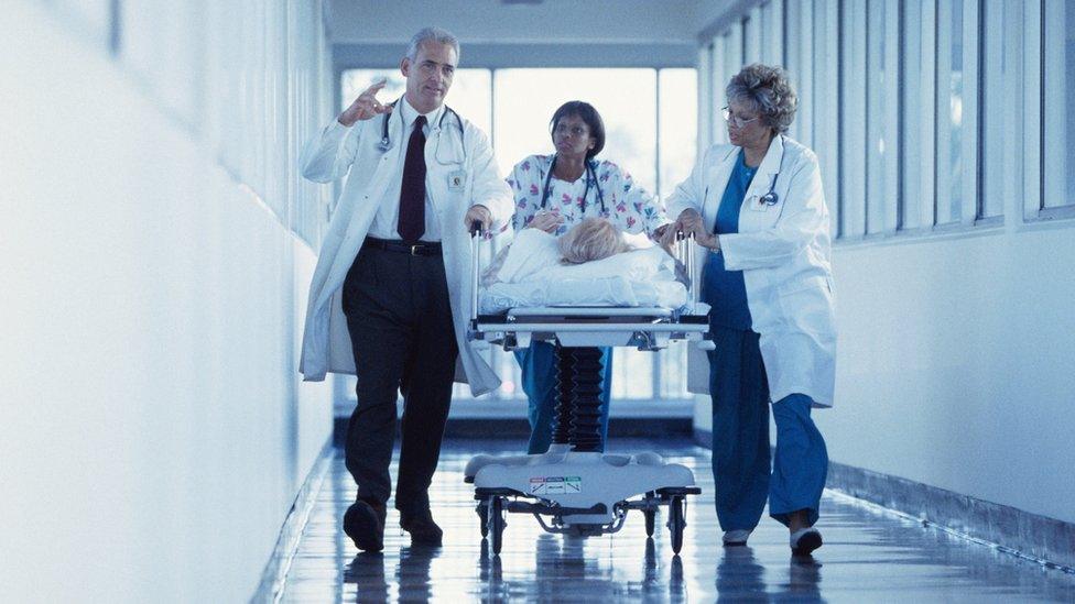 Doctors and a nurse pushing a patient through the hospital corridor