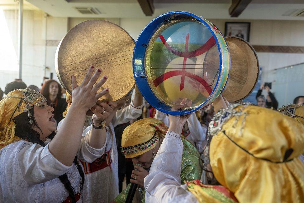 Women play tambourines and sing.