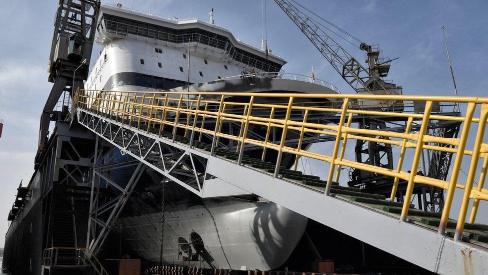 A large ship in dry dock is worked on in this photo from late 2018