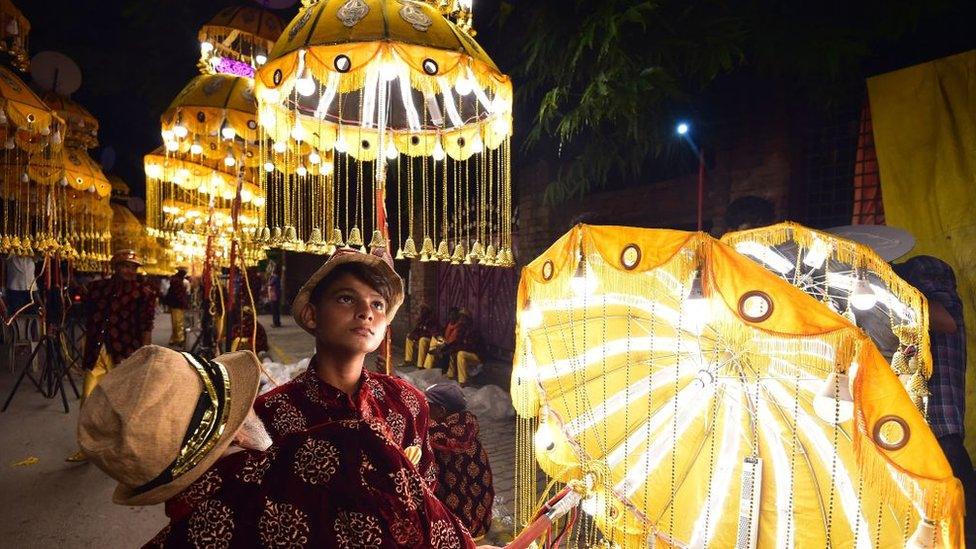 Men holding umbrellas with lights wait before the start of a religious procession on the occasion of 'Dussehra' festival in Allahabad on September 21, 2022.