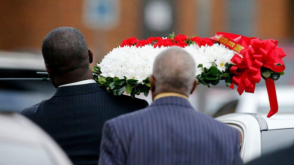 A man carries a wreath of flowers into the funeral service for Botham Jean in September, 2018