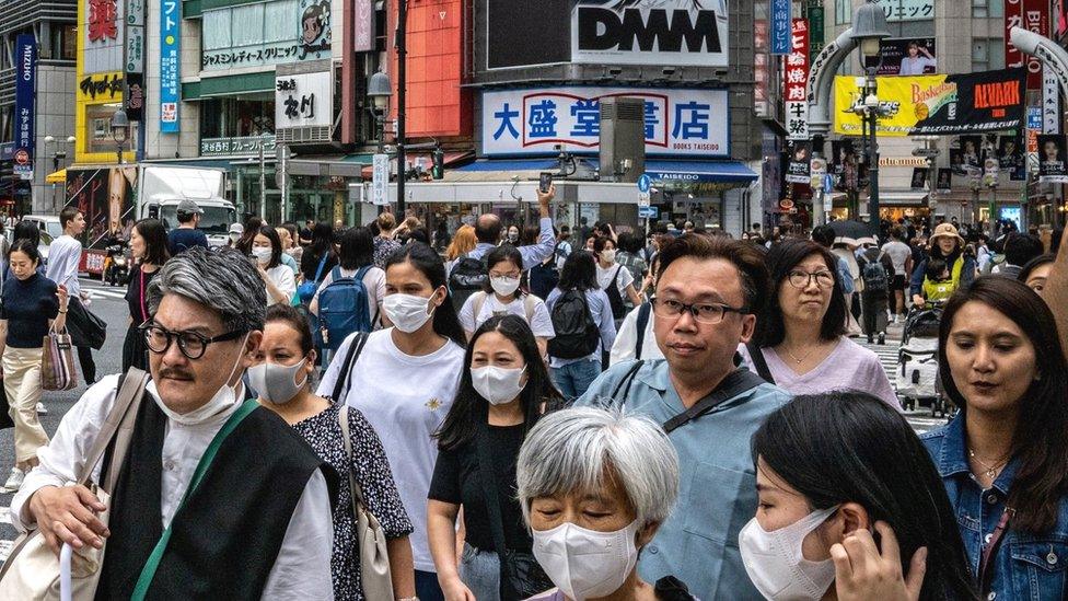 People walk across the Shibuya Crossing in Tokyo.