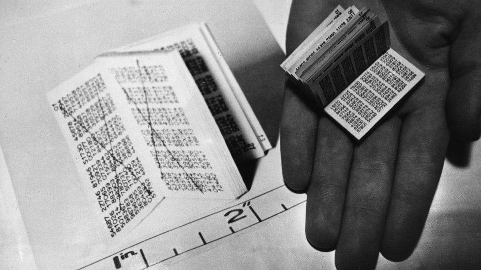 A codebook full of tiny numbers, held in an open palm