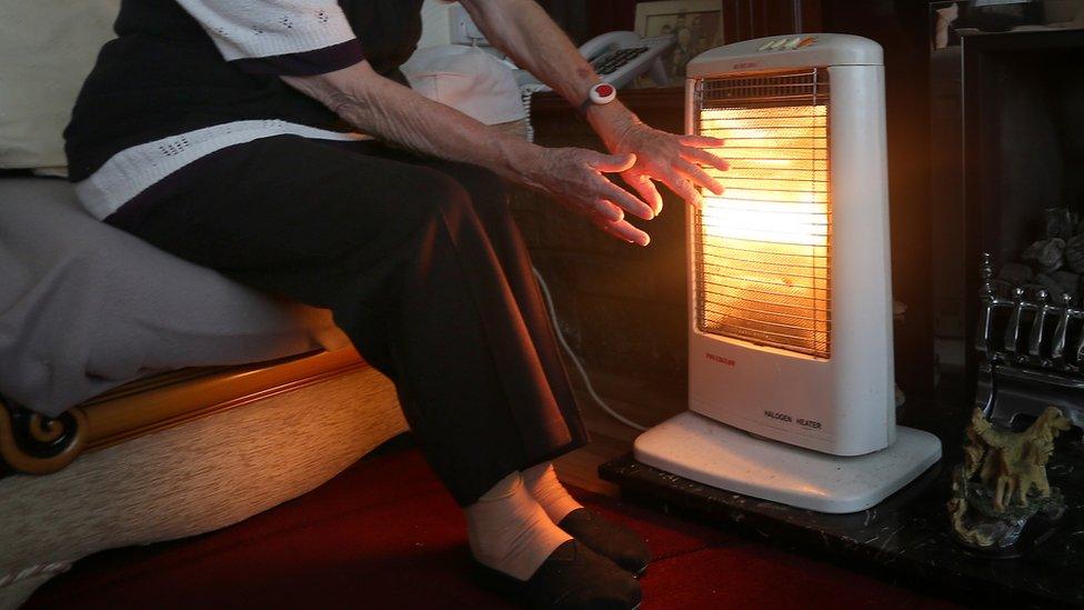 An elderly lady with her electric fire on at home