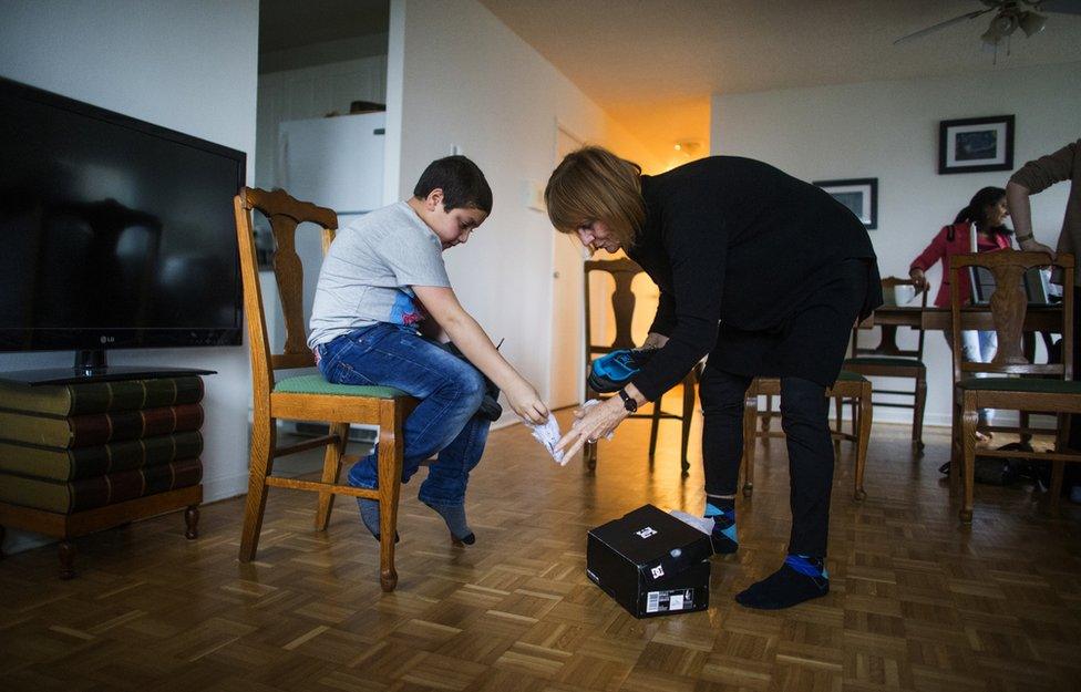 Syrian refugee sponsor Valerie Pringle helps refugee Nasimi Al Hasan put on the new shoes she bought him inside their apartment in Mississauga, Ontario, Canada, Thursday January 21, 2016.