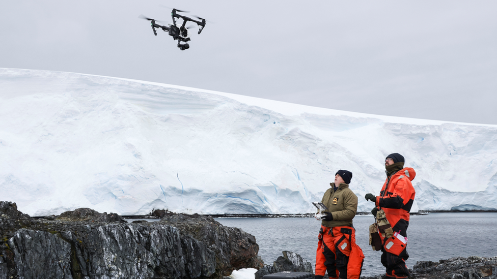 Sailors flying drones in front of the ice