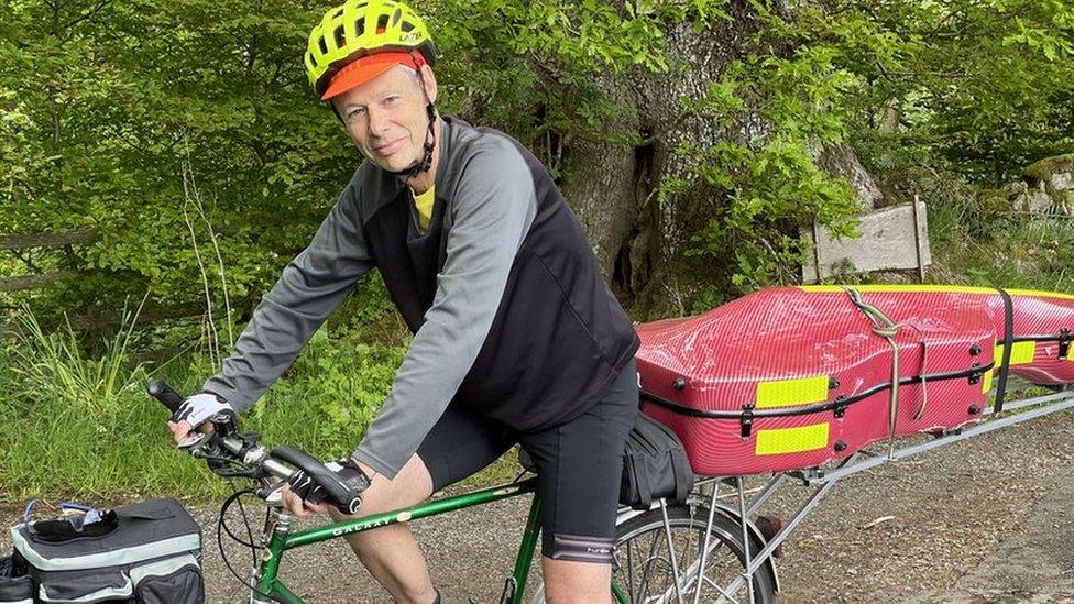 Kenneth on bike with cello behind