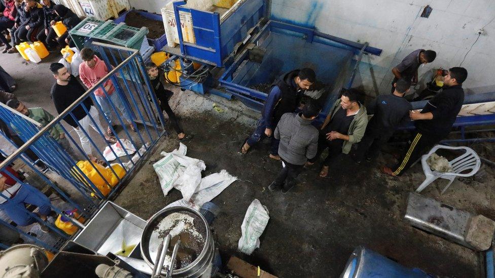 Palestinians wait to get their olives pressed at an oil mill during a ceasefire in Khan Younis in the southern Gaza Strip on 28 November 2023