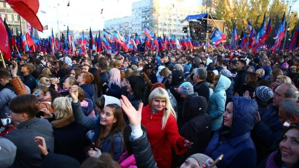 Crowds of people wave flags and hold up phones in the Donetsk Republic as they await their acting leader, Denis Pushilin