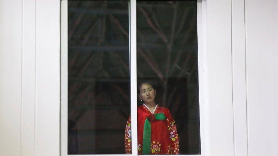 A woman wearing traditional clothes watches taekwondo sportsmen demonstrate their skills to a group of visiting foreign reporters in Pyongyang, North Korea April 17, 2017