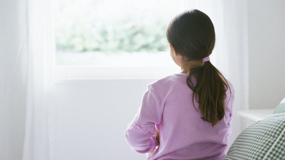 An young girl sitting on a bed