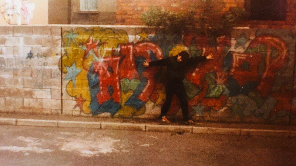 Malcolm P Murphy in front of a piece of his graffiti