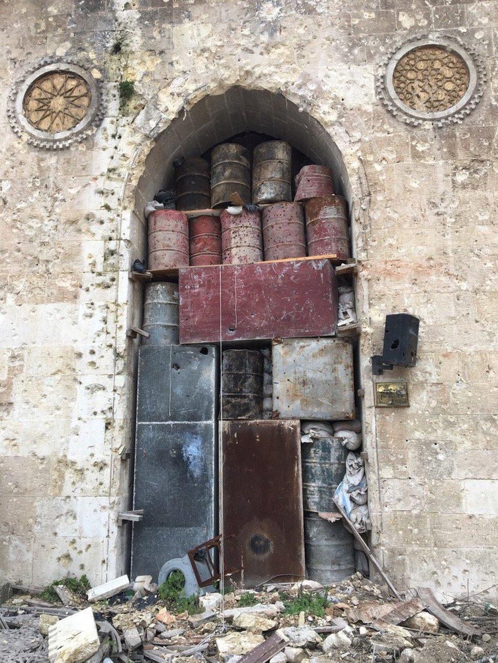 Barrels and boxes stacked up in an archway to prevent bombing damage