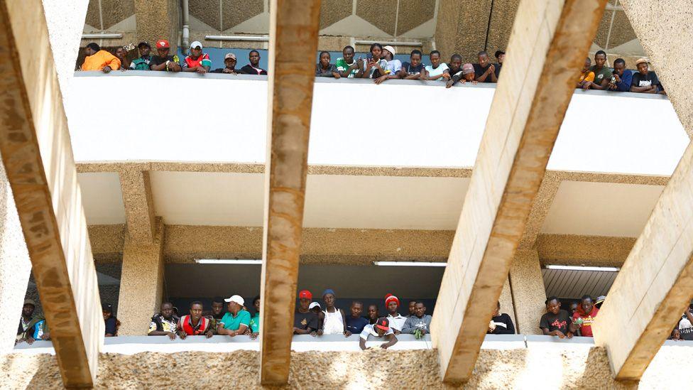 Crowds in a a stadium are pictured from below looking down on as pallbearers (not seen) as they carry the coffin of former Kenyan Prime Minister Raila Odinga inside.