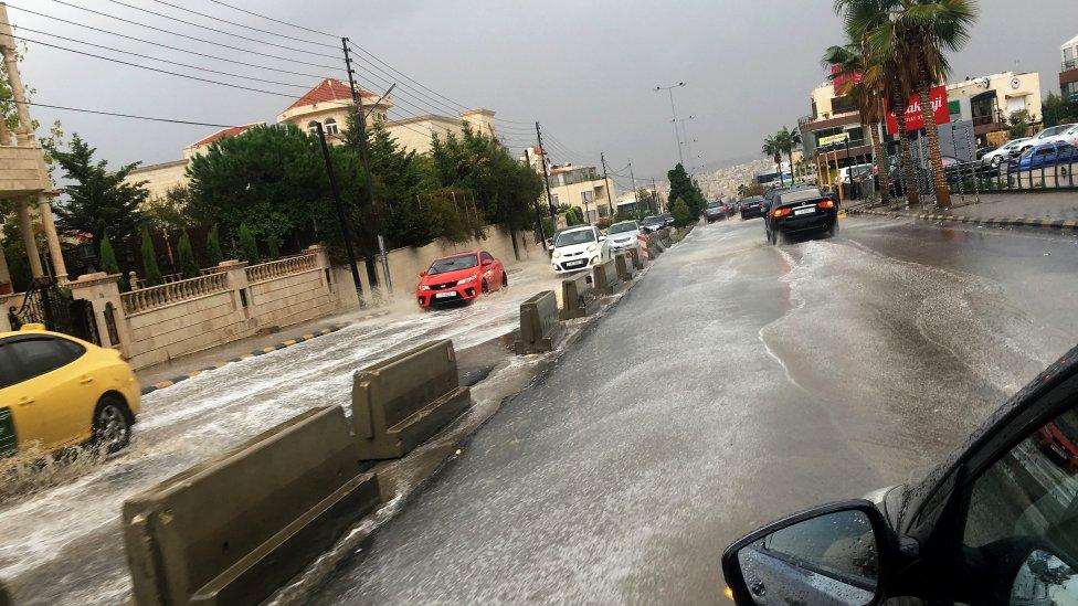 Vehicles drive through rain water after a sudden thunderstorm, at a street of Amman, Jordan, 25 October 2018