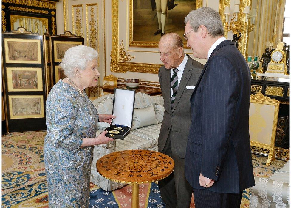 Queen Elizabeth II talks with the Australian High Commissioner Alexander Downer (R) as she prepares to present the Prince Philip, Duke of Edinburgh with the Insignia of a Knight of the Order of Australia, in the white drawing room at Windsor Castle on 22 April 2015 in Windsor, England.