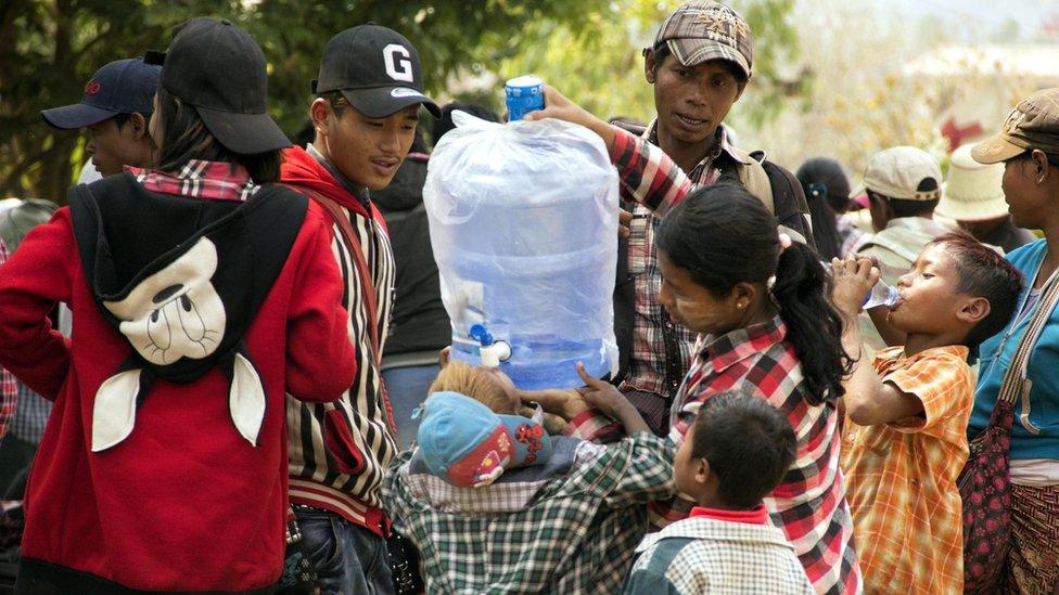 Refugees fleeing the conflict at the China-Myanmar border town of Laukkai drink water as they await transportation, 7 March 2017