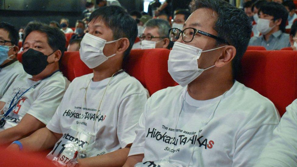 Three men with masks and numbered t shirts