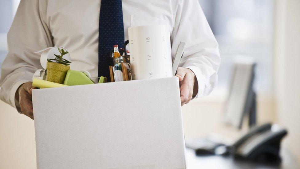 A man holds a box of work things