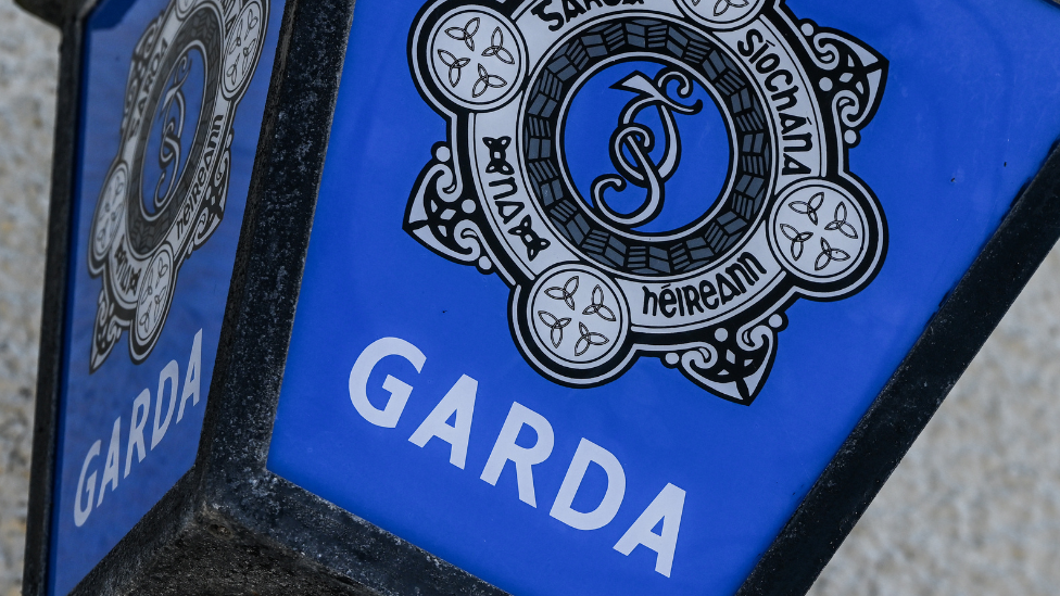 A blue garda sign on a grey stone building. 