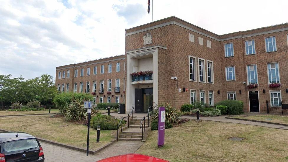 The exterior of Royal Borough of Windsor and Maidenhead - a glass-fronted building with a brick section to the left of the main entrances, and well-established trees and steps in front