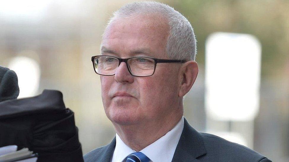 A tight head shot of a tight-lipped Paul Mowat outside Glasgow Sheriff Court. He is wearing dark-rimmed glasses, a dark navy suit, white shirt and blue and white striped tie.