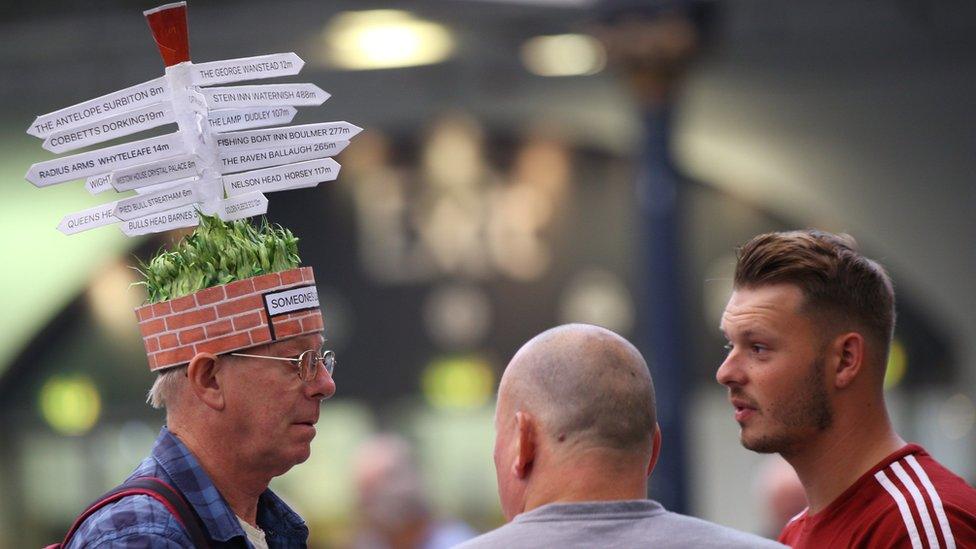 Man with road sign hat chats to visitors during the traditional hat day during the CAMRA Great British Beer Festival at Olympia in London