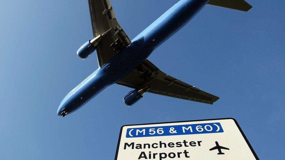 plane-flying-over-manchester-airport-sign