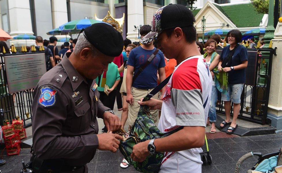 A Thai policeman searches a visitor's bag at the Erawan Shrine, Bangkok, on 13 August 2016.