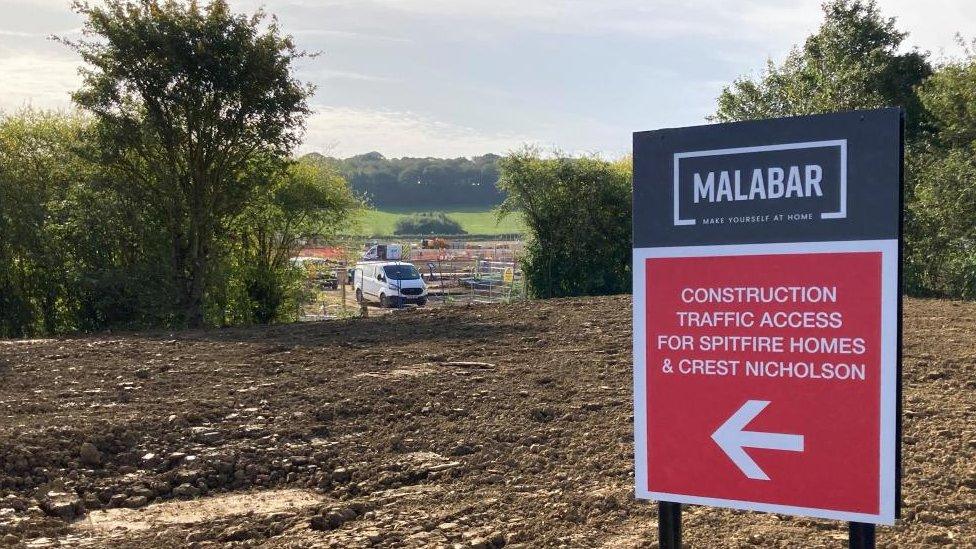 Muddy construction site with Malabar sign in foreground