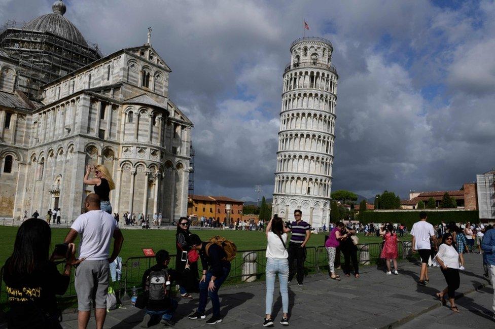 Tourists pose for photographs at the Leaning Tower of Pisa