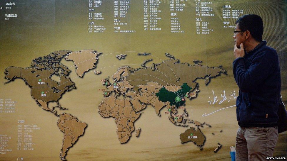 A Chinese investor walks past an investment map showing suitable property markets for wealthy Chinese to invest in at the International Property Expo in Beijing on April 11, 2014.