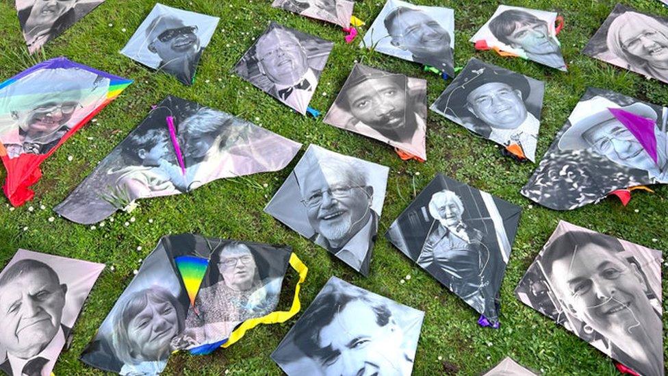 A number of kites on the ground as part of a covid memorial event