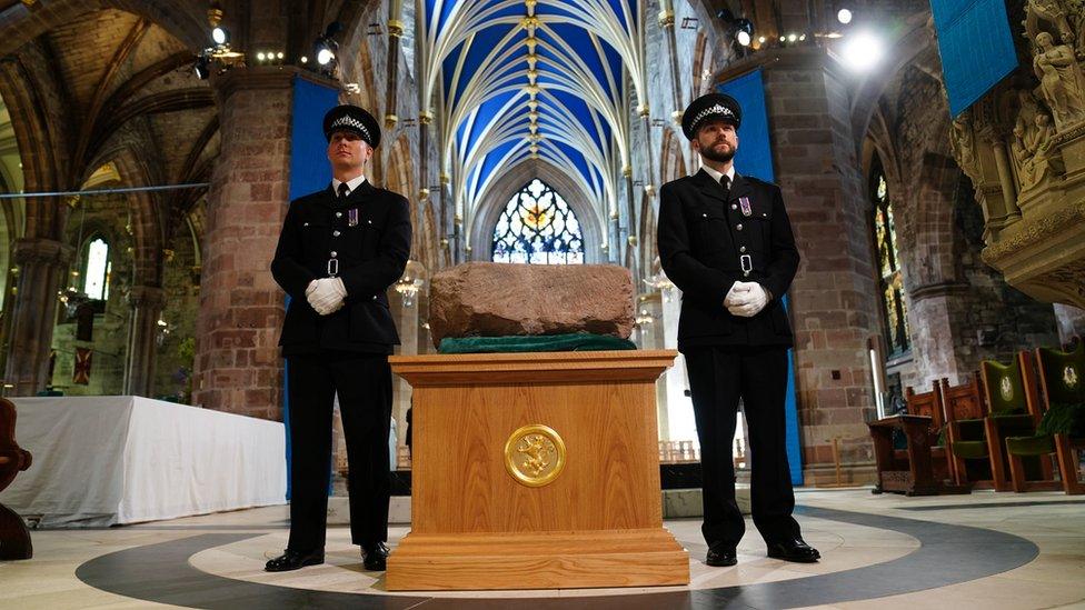 Two officers standing either side of a plinth holding the Stone of Destiny or the Stone of Scone inside St Giles' Cathedral