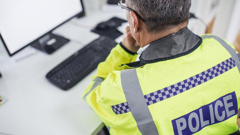 An older police officer sat at a computer